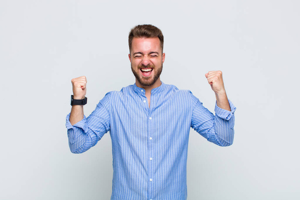 young man looking extremely happy and surprised, celebrating success, shouting and jumping - 写真・画像