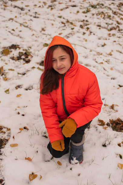 una chica con una chaqueta cálida naranja brillante. Chica con una chaqueta naranja en clima nevado. Adolescente chica en invierno - Foto, Imagen