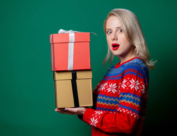 Beautiful woman in Christmas sweater with gift box on green background - Valokuva, kuva