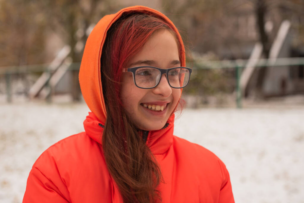 Parlak turuncu ceketli bir kız. Karlı havada turuncu ceketli bir kız. Kışın genç kız - Fotoğraf, Görsel