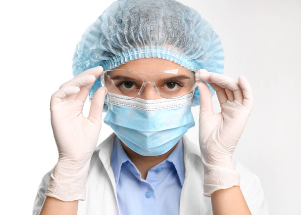 Doctor with medical gloves, mask, cap and protective goggles on white background - Foto, Imagen