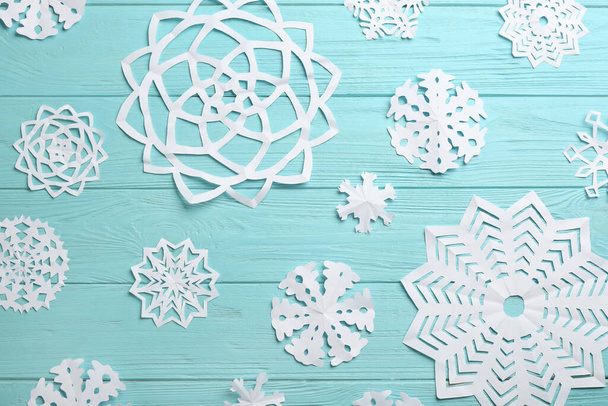 Many paper snowflakes on turquoise wooden background, flat lay - Foto, imagen