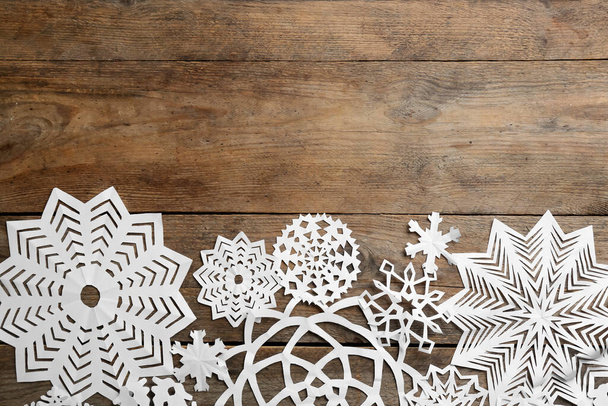 Many paper snowflakes on wooden background, flat lay. Space for text - Zdjęcie, obraz