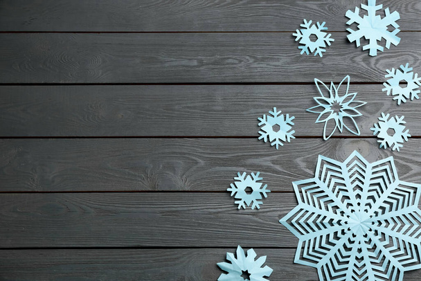 Many paper snowflakes on grey wooden background, flat lay. Space for text - Photo, Image