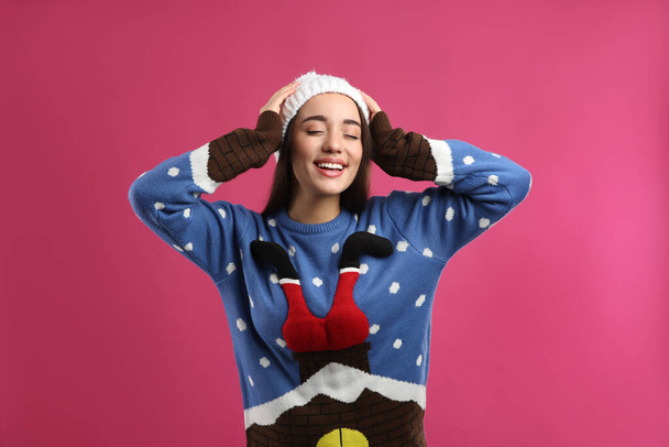 Young woman in Christmas sweater and hat on pink background - Photo, image