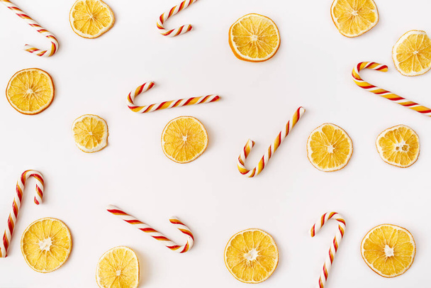 Christmas, winter, new year composition. Slices of dry oranges and candies on white background. Food background. Flat lay, top view - Photo, image