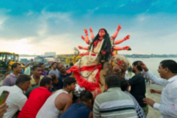 Durga istennő bálványának elmosódott képét a Gangesz folyóba viszik merítés céljából, a Durga Puja fesztivál végén. Az esemény neve Bisorjon Bengáliban. - Fotó, kép
