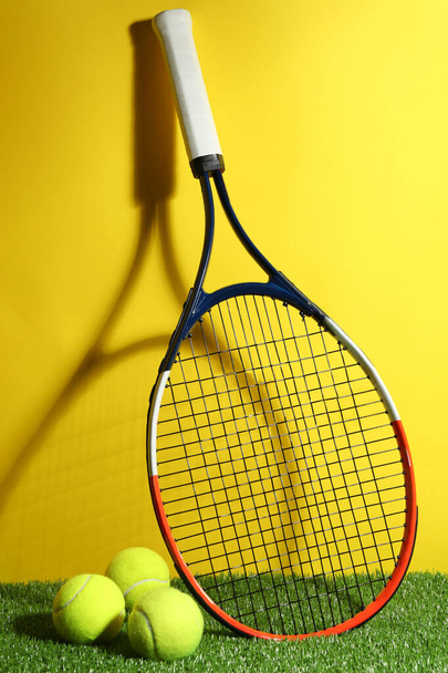 Tennis racket and balls on green grass against yellow background. Sports equipment - Foto, immagini