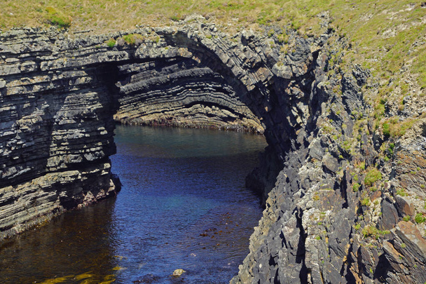 The Bridge of Ross. A natural bridge formed by the Ross Sandstone of Carboniferous age. County Clare, Ireland.The bridges of Ross were a trio of spectacular natural sea bows - at least until two of them fell into the sea. Today there is only one "bri - Фото, изображение