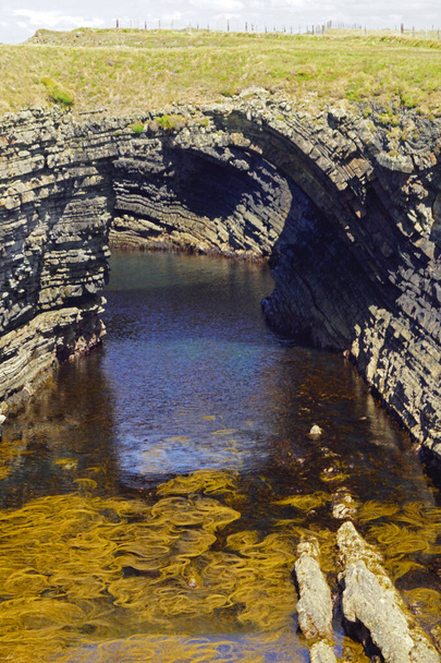 The Bridge of Ross. A natural bridge formed by the Ross Sandstone of Carboniferous age. County Clare, Ireland.The bridges of Ross were a trio of spectacular natural sea bows - at least until two of them fell into the sea. Today there is only one "bri - Valokuva, kuva