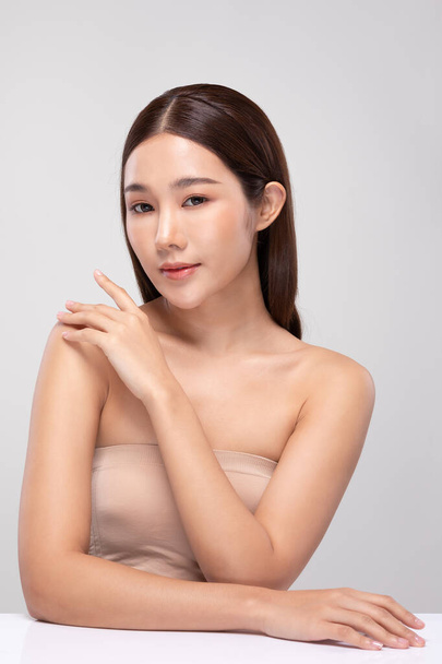 Beautiful Young Asian Woman Looking While Touching Shoulder feeling so happy and cheerful with healthy Clean and Fresh skin,isolated on gray background,Beauty Cosmetology Concept - Fotoğraf, Görsel