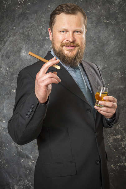 Solid confident bearded man in suit with glass of whisky and cigar - Photo, image