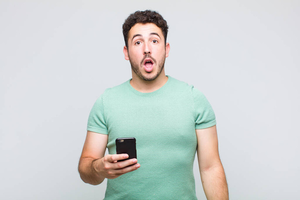 young man looking very shocked or surprised, staring with open mouth saying wow - 写真・画像