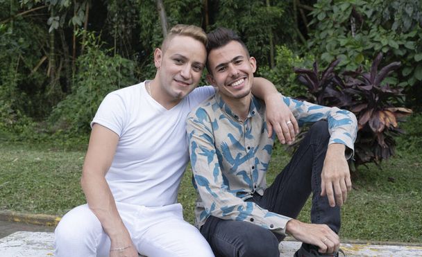 Portrét homosexuálního páru v parku, dali hlavy dohromady a jeden z nich položil ruku druhému na krk. - Fotografie, Obrázek