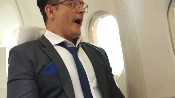 Schläfriger Geschäftsmann reist auf Geschäftsreise mit dem Flugzeug - Foto, Bild