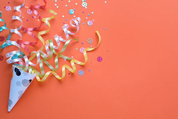 Colorful confetti and streamers with party cracker on orange background, top view. Space for text - Foto, immagini