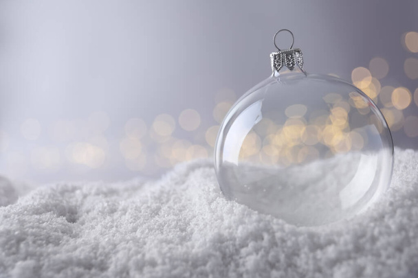Transparent Christmas ball on snow against blurred fairy lights, space for text - Φωτογραφία, εικόνα