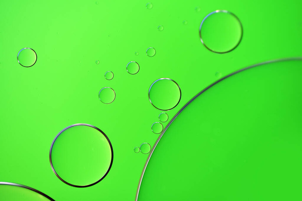 Abstracte belletjes (plantaardige olie op water) op een groene achtergrond - Foto, afbeelding