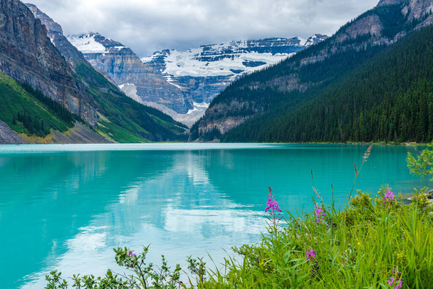 Lake Louise in summer sunny day morning. Blue sky and white clouds reflected on the turquoise color lake water surface. Beautiful landscape in Banff National Park, Alberta, Canada. - Photo, image