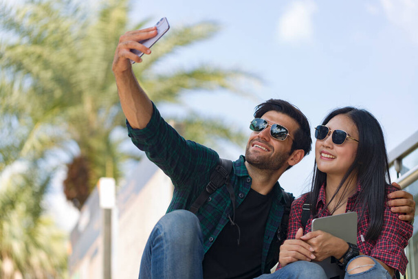 Voyageurs en couple prenant une photo avec leur téléphone tout en étant assis et se reposant du voyage. - Photo, image
