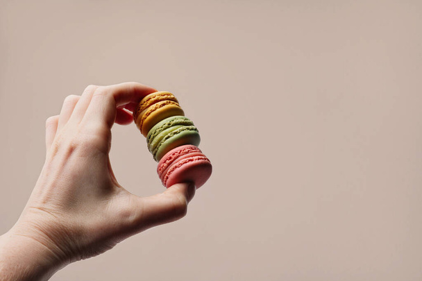 Human hand holding crunchy delicious macarons. Sweets and desserts. Copy space. - Фото, изображение