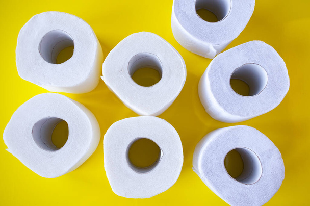 Pile of rolls of white toilet paper on a yellow background, top view - Photo, image