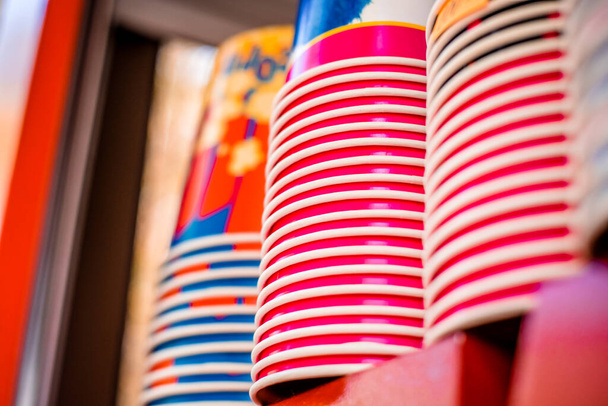 Lots of multi-colored paper cups. A stack of popcorn paper cups. A stack of popcorn paper cups on a showcase - Фото, зображення