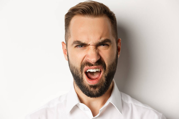 Emotions and people concept. Close-up of shocked bearded man reacting to something disappointed, complaining and grimacing, white background - Valokuva, kuva