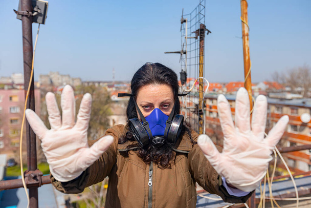 Medya baskısını durdurun. Endüstriyel maske takan kadının yüzünde kağıt filtre var. Elleri, hareketi, sosyal mesafesi, uzak durması, COVID-19 virüsüne karşı korunması, Corona. - Fotoğraf, Görsel