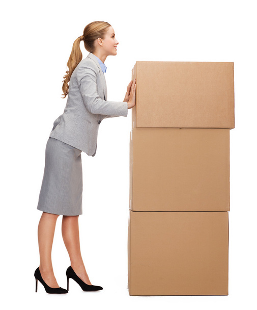 Smiling businesswoman pushing tower of cardboards - Фото, изображение