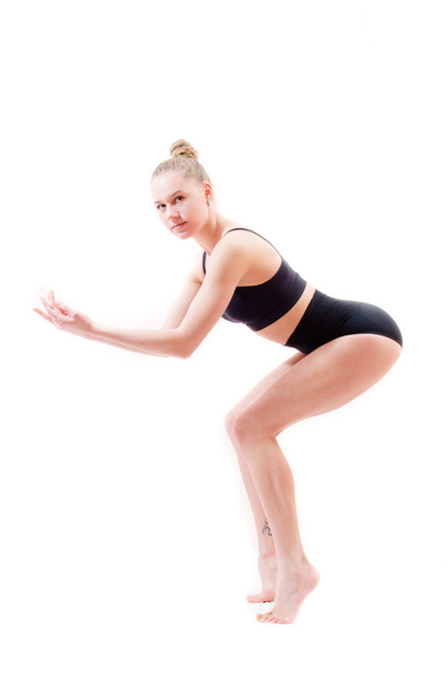 atraktivní mladá žena sportovní flexibilní dívka v černém obleku na bílém pozadí při pohledu na fotoaparát - Fotografie, Obrázek
