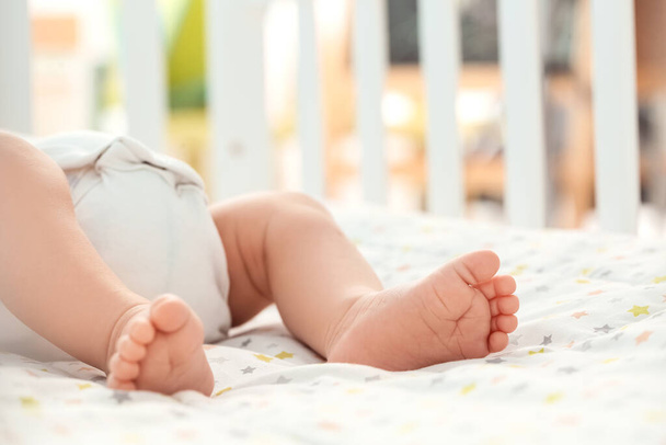 Legs of cute little baby lying in crib - Photo, Image