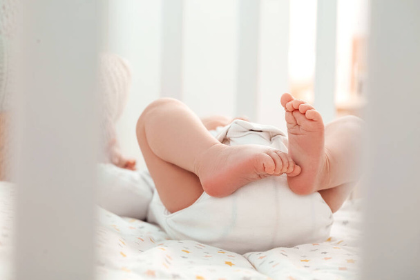 Ноги милої маленької дитини, що лежить в ліжку
 - Фото, зображення