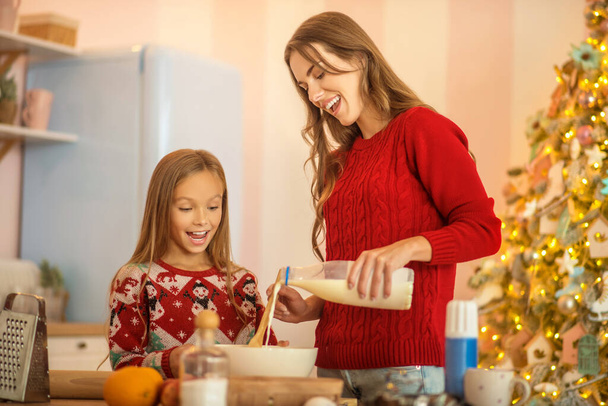 Kid and her mom cooking together in the kitchen - 写真・画像