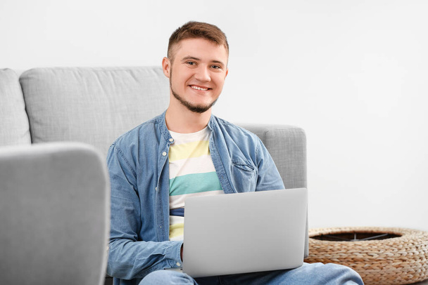 Νεαρός που χρησιμοποιεί φορητό υπολογιστή στο σπίτι - Φωτογραφία, εικόνα