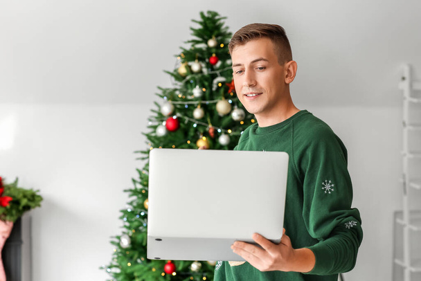 Fiatal férfi laptoppal otthon karácsony este - Fotó, kép