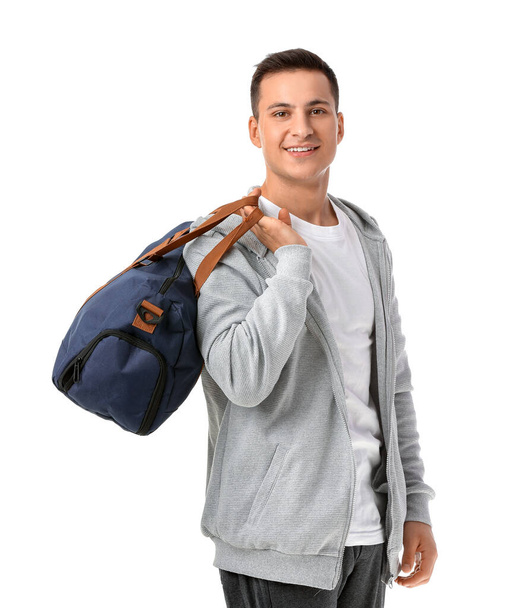 Спортивный молодой человек с сумкой на белом фоне - Фото, изображение