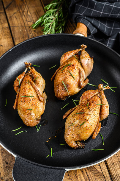 Homemade roast pigeon quail in a pan. Wooden background. Top view. - Photo, Image