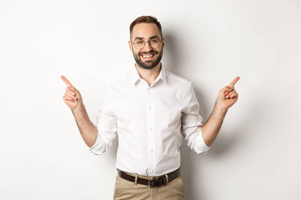 Confident bearded man smiling, pointing left and right at copy spaces, standing over white background - Photo, Image
