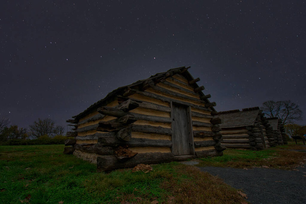 Cabanes en rondins de reproduction au parc historique national de Valley Forge avec un ciel nocturne plein d'étoiles derrière - Photo, image