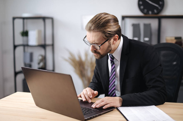 Mann im Anzug arbeitet im Büro am Laptop - Foto, Bild