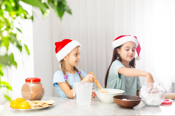 two little girls prepare Christmas cookies in the kitchen - Foto, imagen