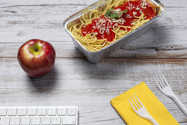 Lunch at workplace homemade and healthy spaghetti with tomato and cheese on work table with computer keyboard. Home food for office concept. Take away food - Zdjęcie, obraz