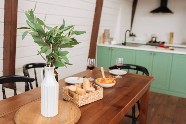 pianta decorativa in vaso bianco sul tavolo con cena vegetariana sfocata sullo sfondo in cucina - Foto, immagini