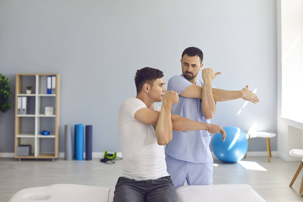 Physiotherapist teaching patient to do cross-body stretch to ease pain and cure shoulder stiffness - Фото, зображення