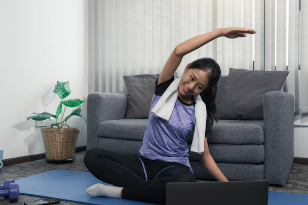 jong aziatische vrouw stretching na haar workout thuis. - Foto, afbeelding