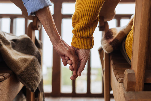 cropped view of elderly couple holding hands on terrace on blurred background - Foto, Bild