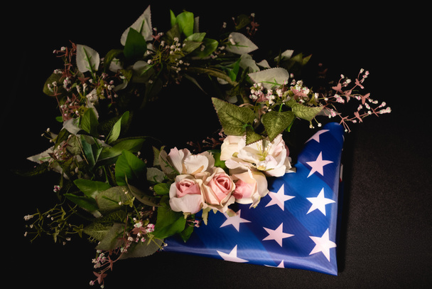corona de rosas y bandera americana sobre fondo negro, concepto funerario - Foto, Imagen