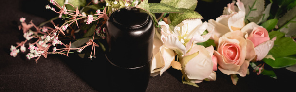 rose bouquet and urn with ashes on black background, funeral concept, banner - Foto, immagini