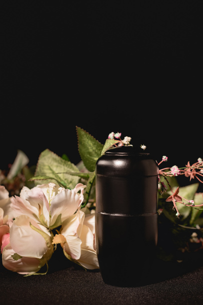 rose bouquet and urn with ashes on black background, funeral concept - Photo, Image